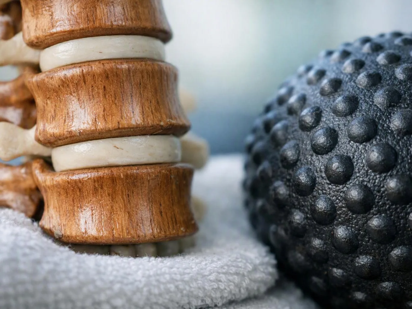 Close-up of a wooden and white stack beside a black textured massage ball on a towel
