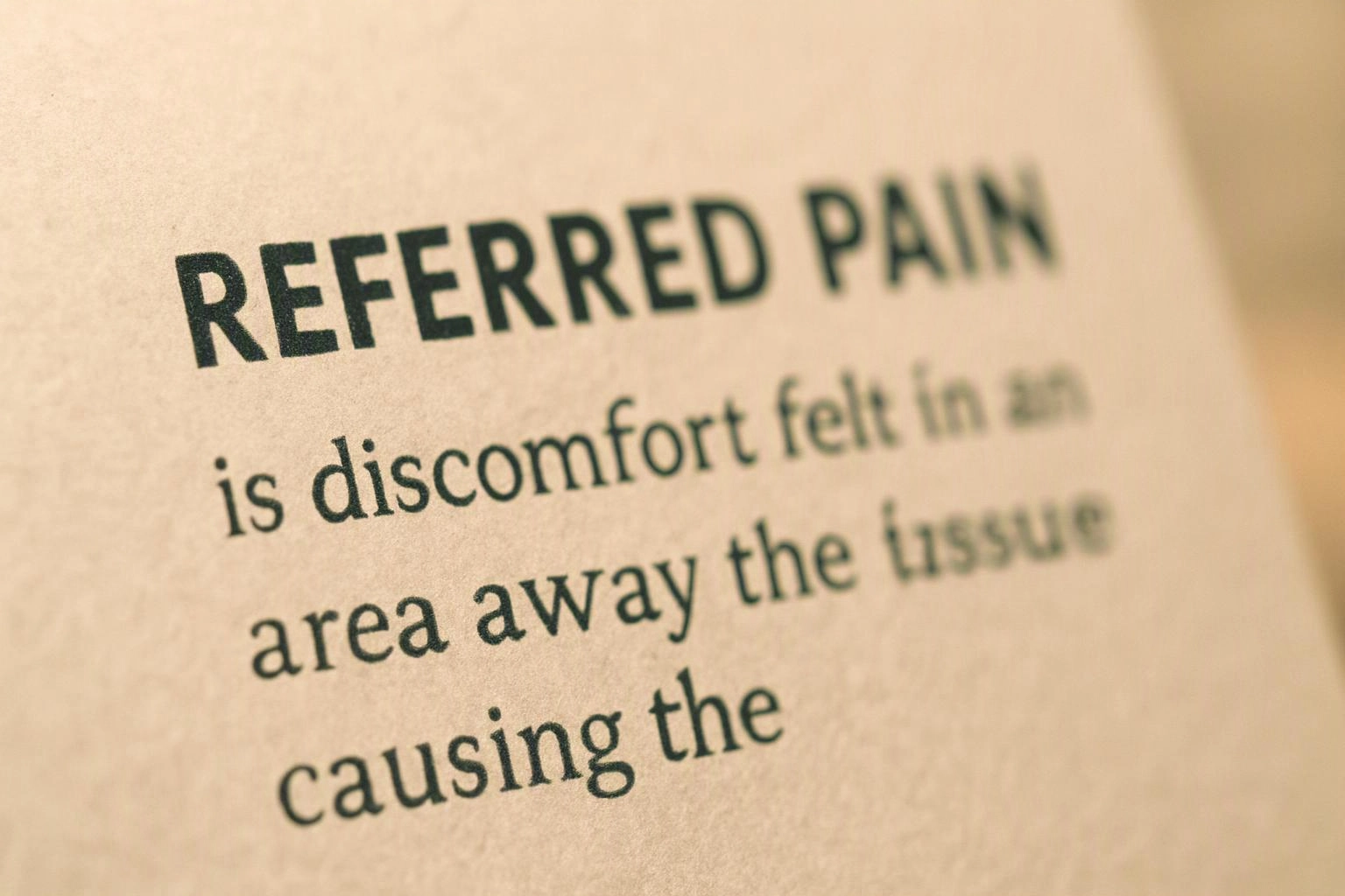 Close-up of a printed page with the bold heading “REFERRED PAIN” and blurred body text beneath